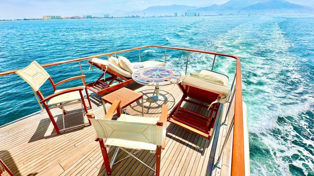 Teak aft deck of a private yacht with Puerto Vallarta's Hotel Zone and the Sierra Madre behind, on a photo charter