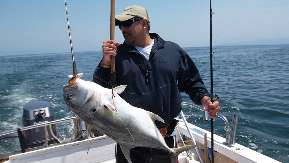 Angler holding a freshly caught jack on a fishing charter off Puerto Vallarta
